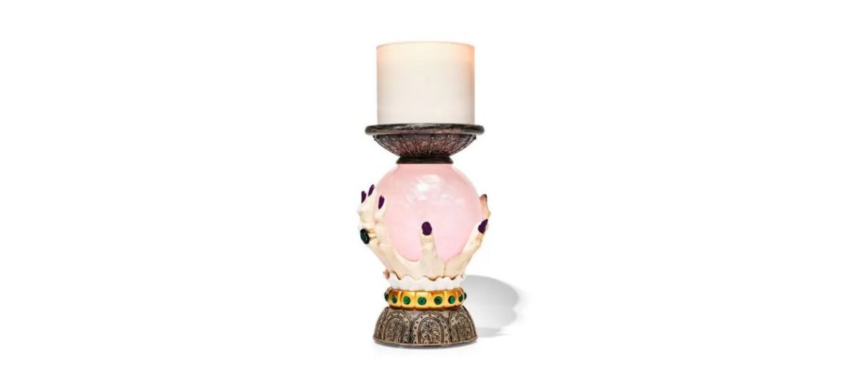 a candle holder that looks like a hand holding a crystal ball with a little plate on top for the candle