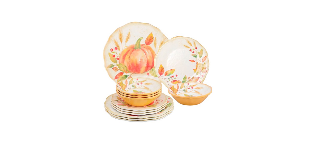 A set of white, orange and gold plates and bowls that have images of fall leaves, pumpkins and wheat