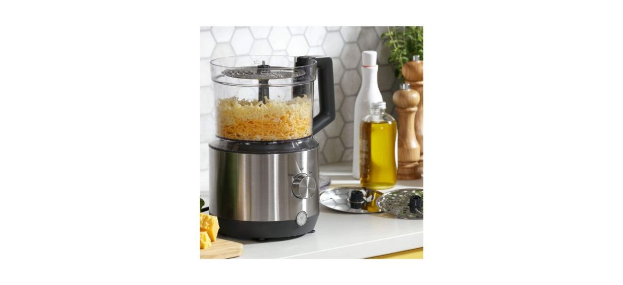 GE 12-Cup Food Processor with cheese in it sitting on a counter in a kitchen