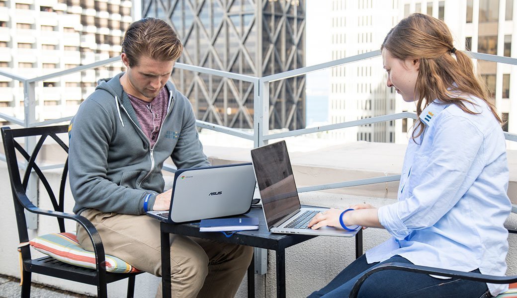 Two people on laptops sitting at a table