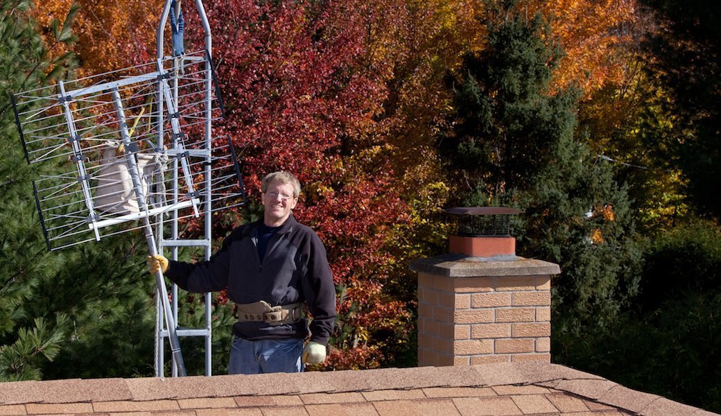 Man installing outdoor tv antenna on roof