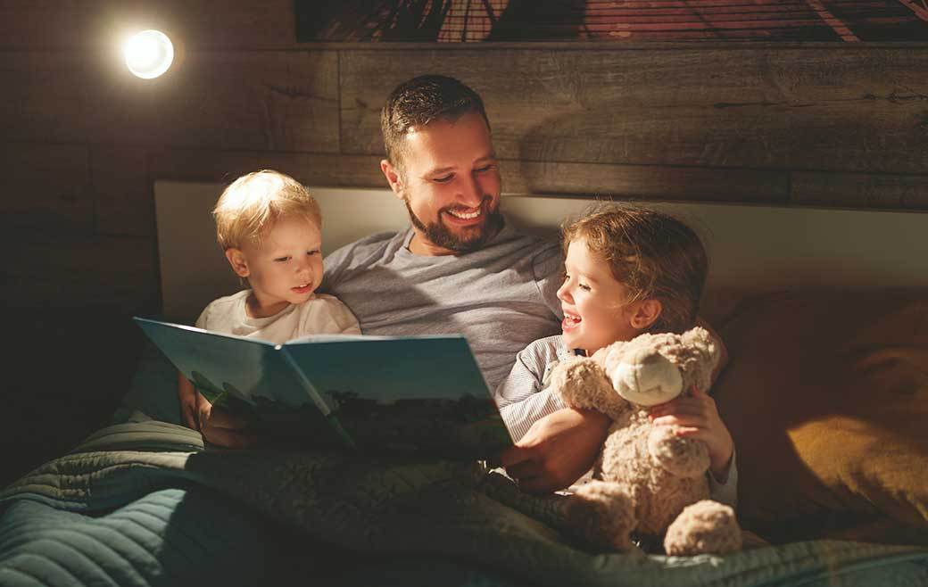 An adult reading to two children