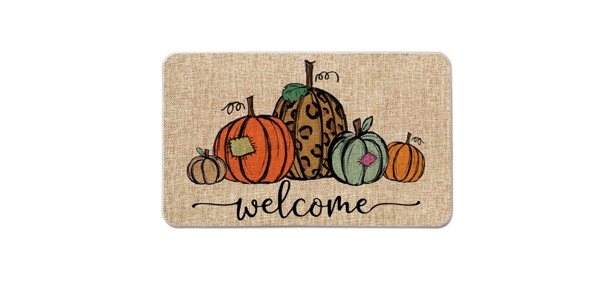 A tan doormat with the word &quot;welcome&quot; on it and designs of orange, tan, cheetah print and green pumpkins on it.