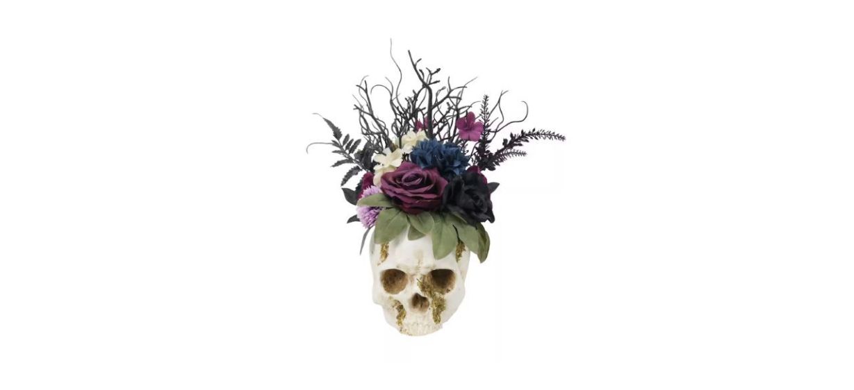 white, purple, black and navy flowers inside a skull-shaped planter