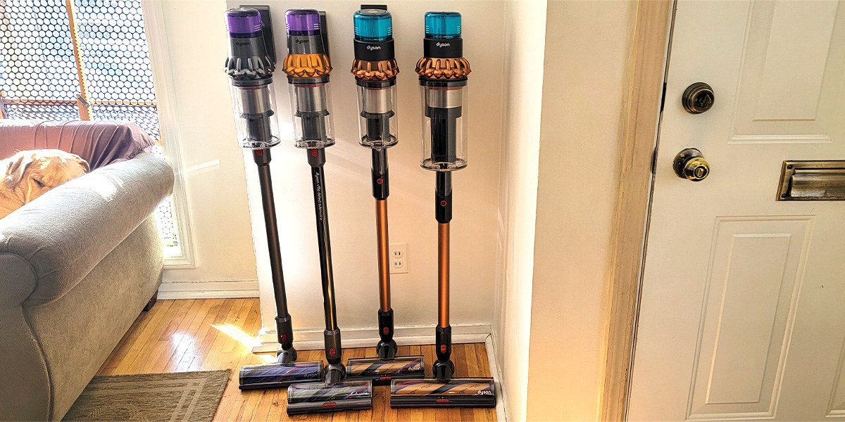 Four cordless vacuums leaning against wall