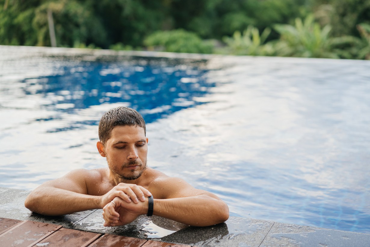 man looking at watch while in the pool