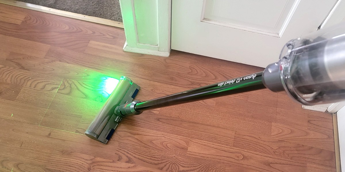 Dyson V12 Slim Detect on hardwood floor with front light on