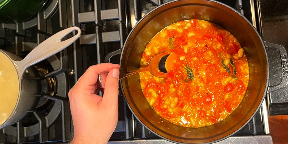 Hand using spoon to stir food in Staub Cast Iron Dutch Oven